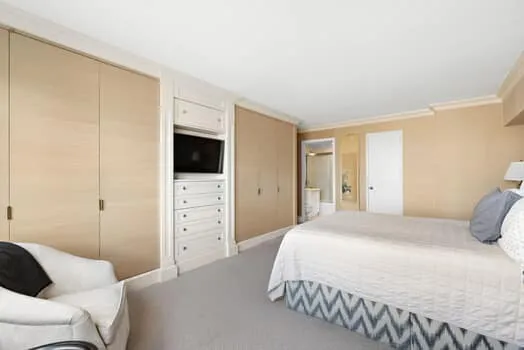 a bedroom with a bed a couch and a flat screen tv