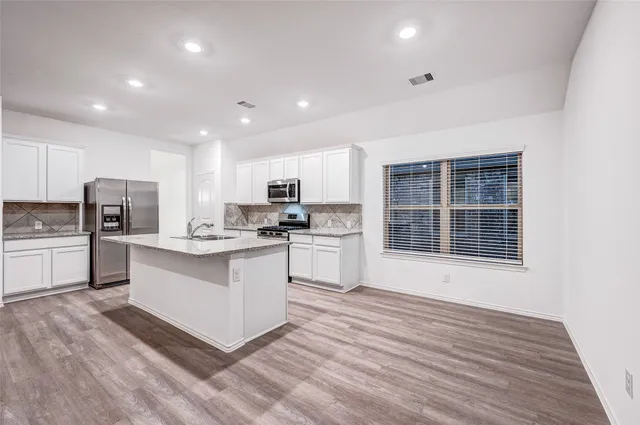 a kitchen with refrigerator cabinets and wooden floor