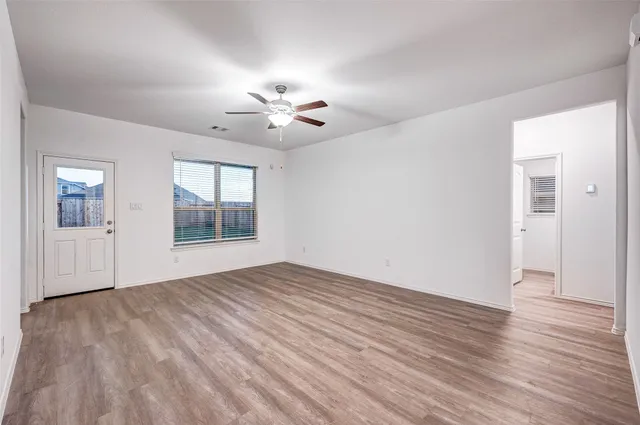 a view of an empty room with a window and wooden floor