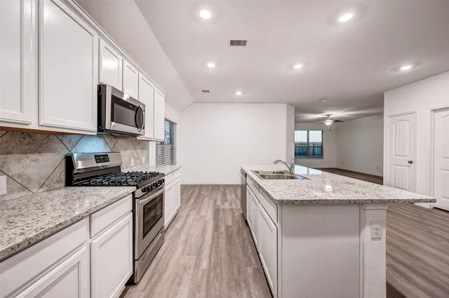 a kitchen with granite countertop kitchen island stainless steel appliances a stove sink and cabinets