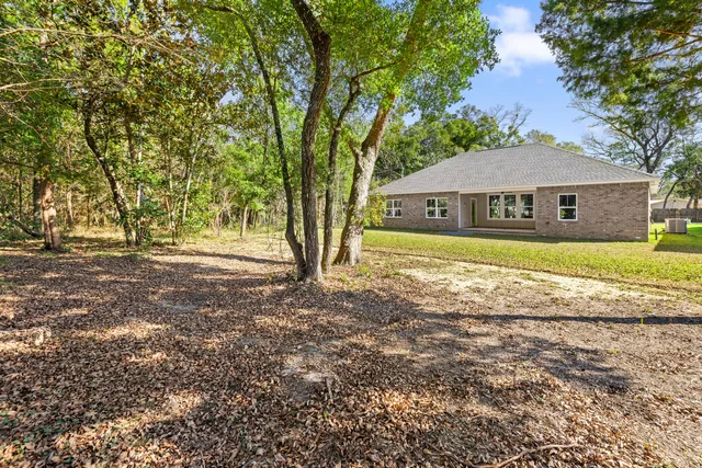 a front view of a house with a garden and trees