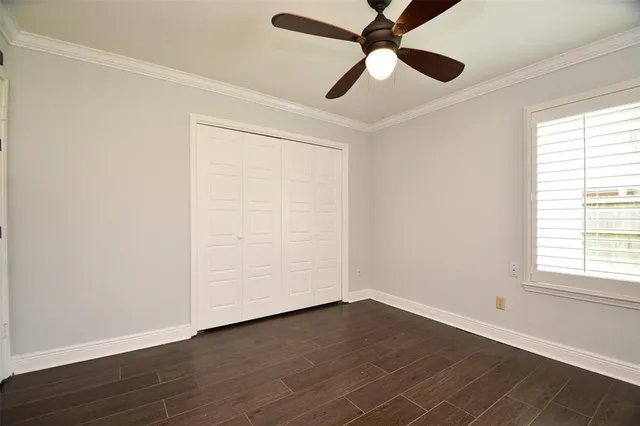 an empty room with wooden floor ceiling fan and windows