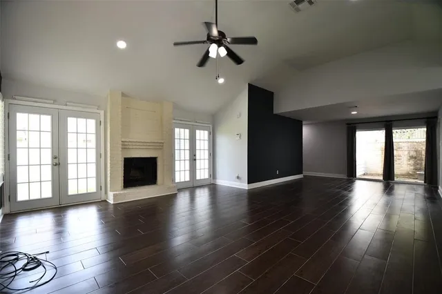 an empty room with wooden floor fireplace and windows