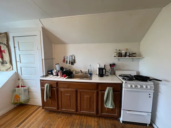 a kitchen with a stove and wooden floor