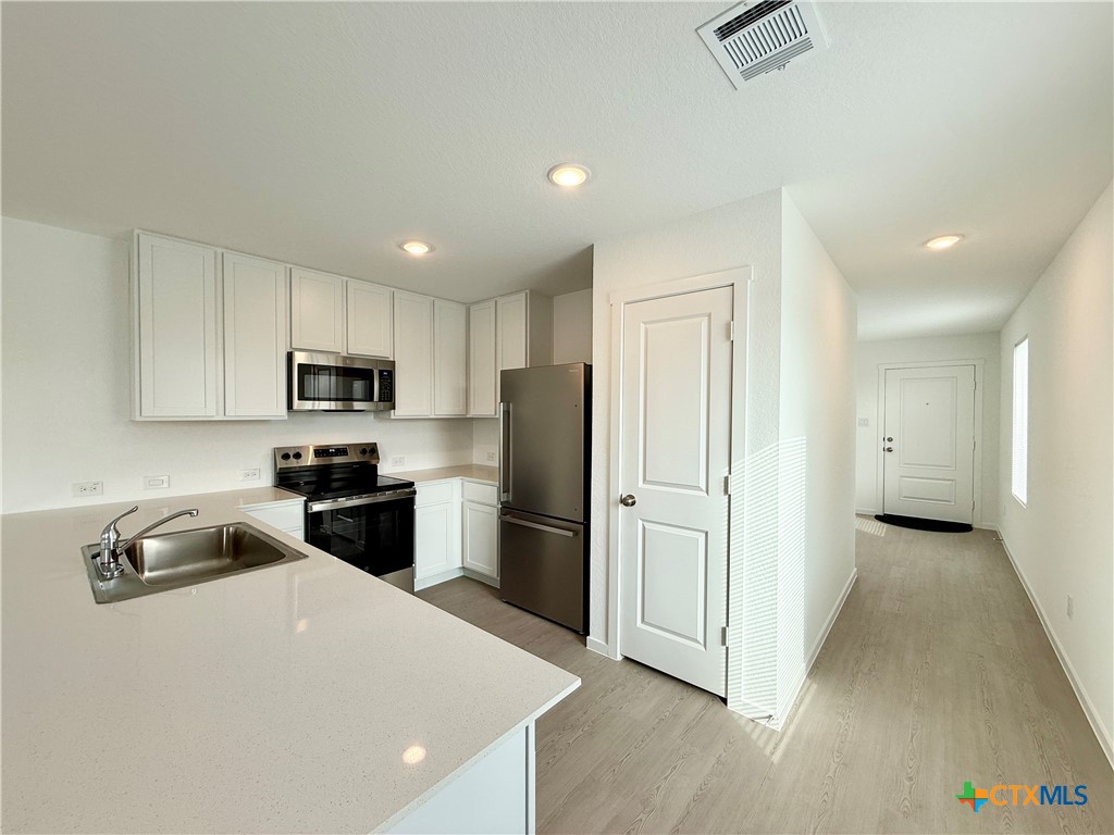 311 Moscato Road New Braunfels, TX 78130 - Photo 4 of 38 a kitchen with stainless steel appliances a refrigerator stove microwave and sink