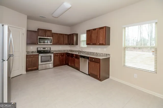 a kitchen with stainless steel appliances granite countertop a stove top oven a refrigerator and a sink