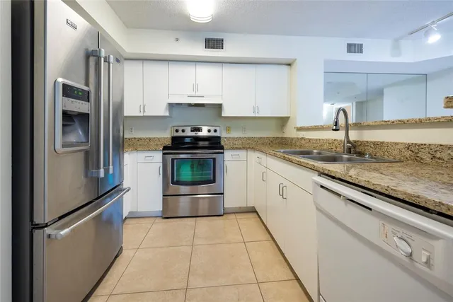 a kitchen with stainless steel appliances granite countertop a sink stove and refrigerator