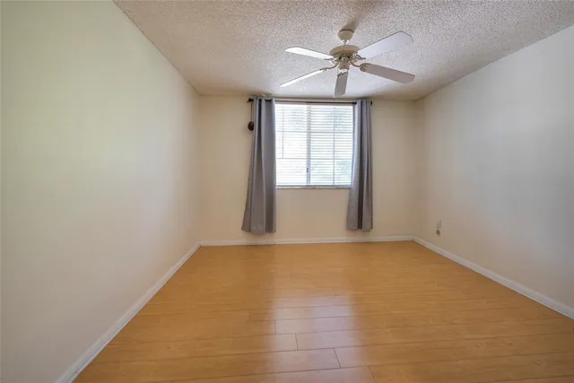an empty room with chandelier fan and windows