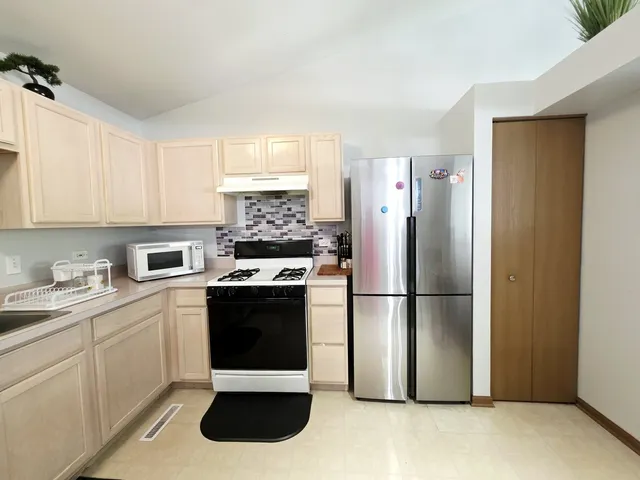 a kitchen with stainless steel appliances granite countertop a refrigerator sink and stove