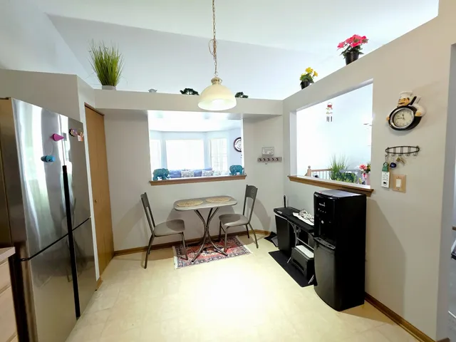 a room with stainless steel appliances kitchen island granite countertop furniture and a refrigerator