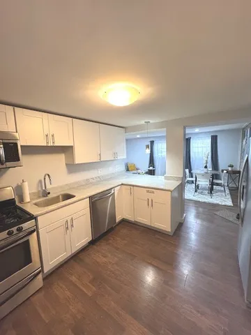 a large kitchen with cabinets wooden floor and stainless steel appliances