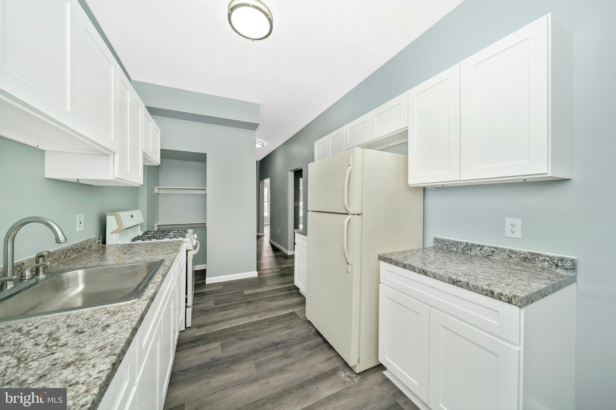 2318 West Lanvale Street Baltimore, MD 21216 - Photo 11 of 37 a kitchen with a sink a refrigerator and cabinets
