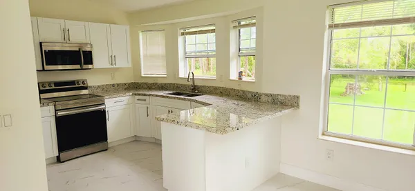 a kitchen with granite countertop a sink stove and microwave
