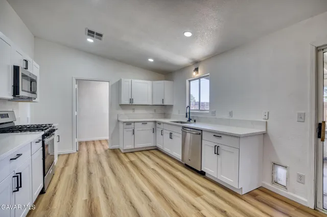 a large kitchen with granite countertop a sink stainless steel appliances and cabinets
