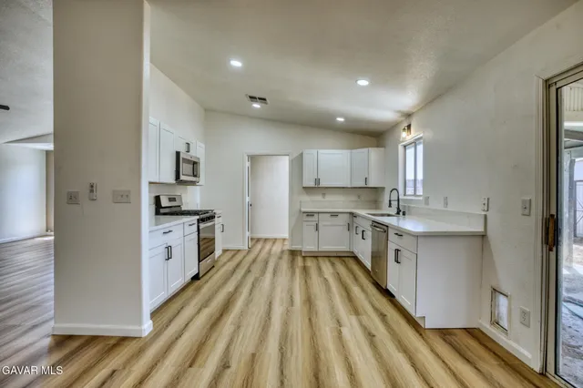 a kitchen with white cabinets appliances and sink