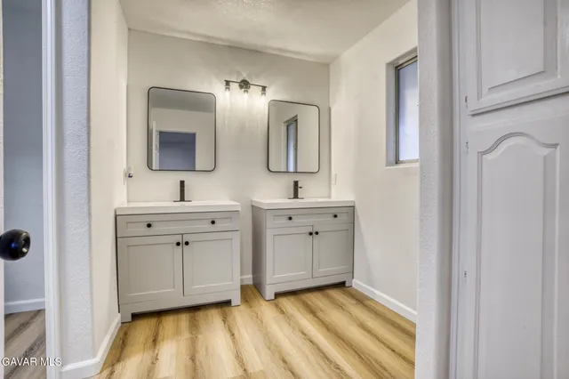 a spacious bathroom with a double vanity sink a mirror and shower