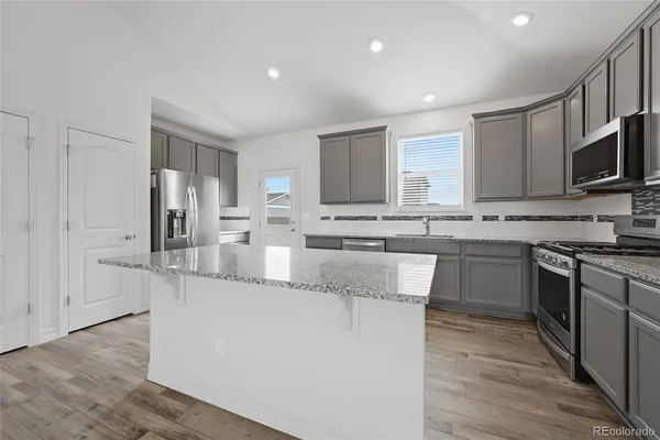 a kitchen with kitchen island granite countertop a stove sink and microwave