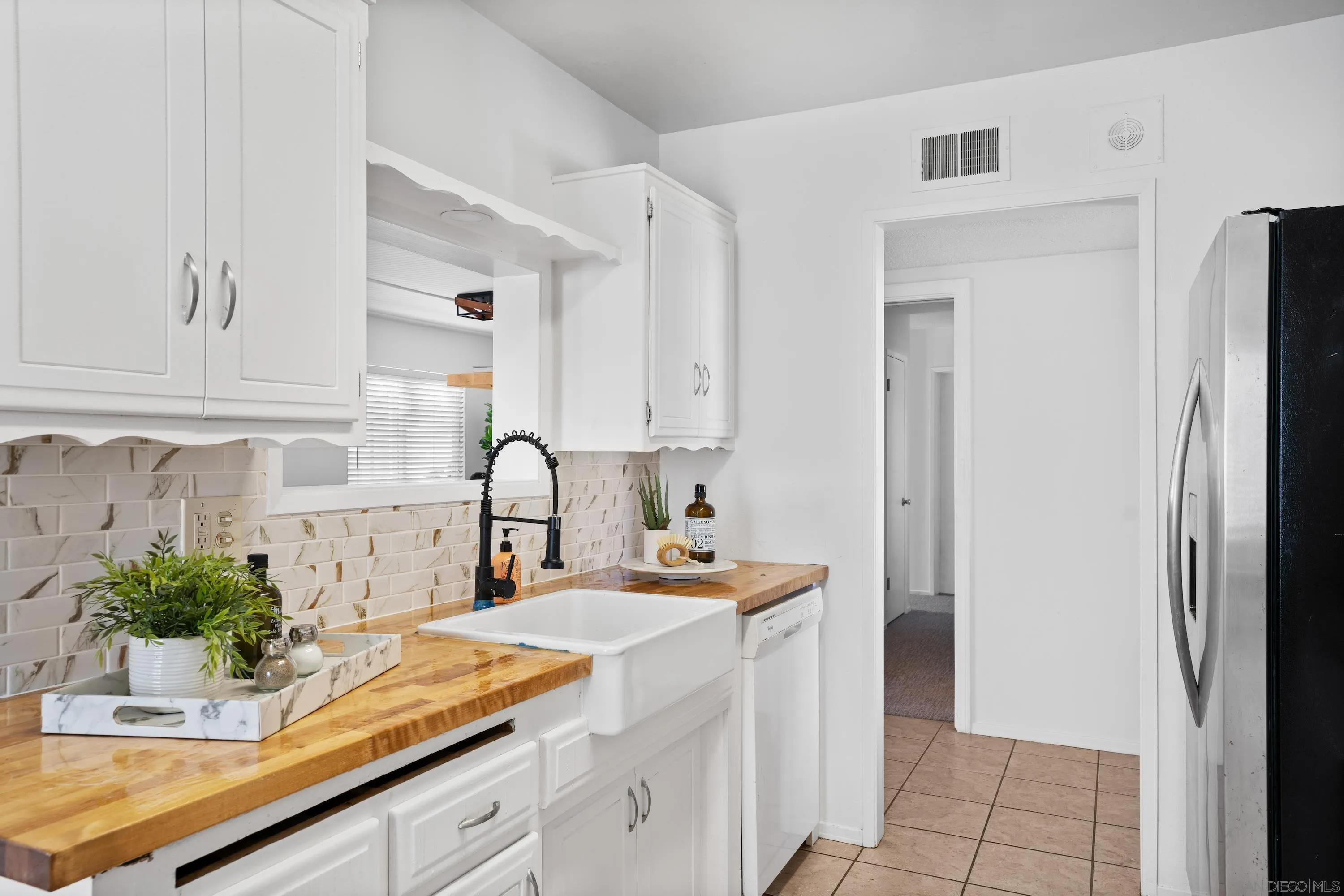 4390 Rolfe Road San Diego, CA 92117 - Photo 11 of 28 a kitchen with stainless steel appliances a sink a window and white cabinets