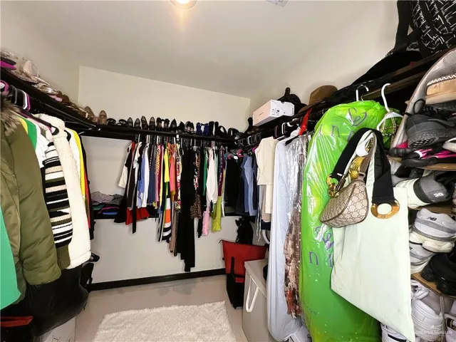 a view of walk in closet with clothes and shoes