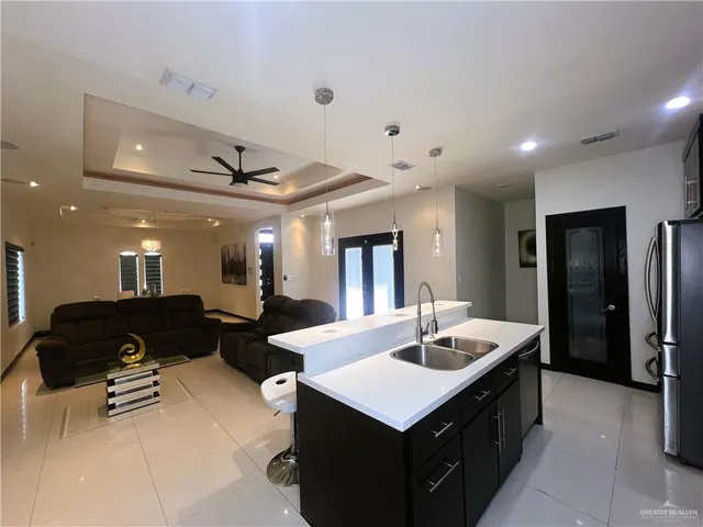 a living room with stainless steel appliances kitchen island granite countertop furniture and a refrigerator