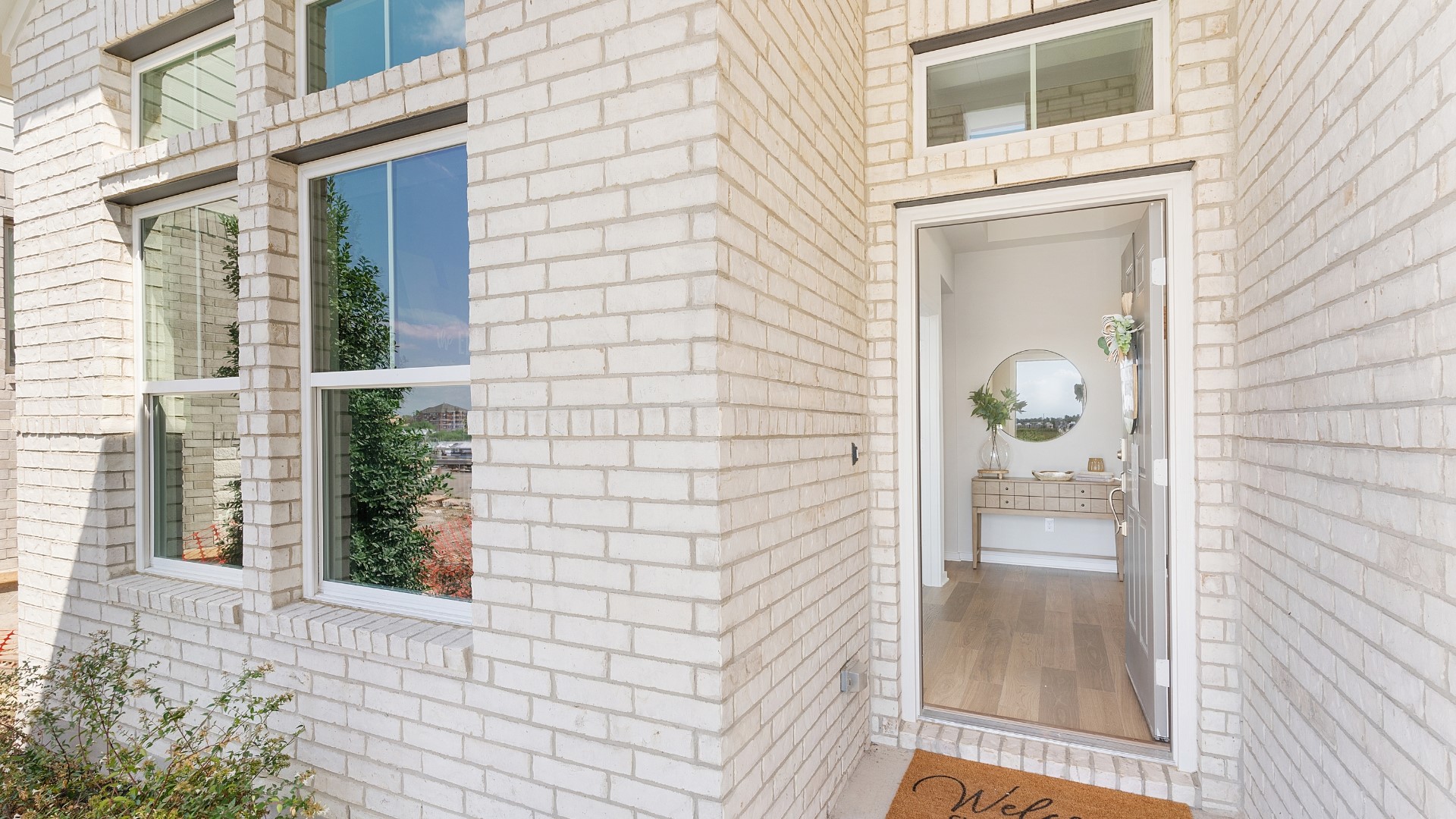 25812 Jasmine Sprig Lane Elgin, TX 78621 - Photo 2 of 33 A cream brick facade welcomes guests through a wide entry, revealing a warm, inviting foyer.