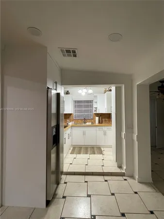 a view of a refrigerator in kitchen and an empty room