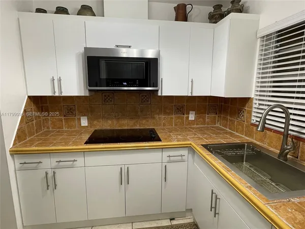 a kitchen with granite countertop white cabinets and stainless steel appliances