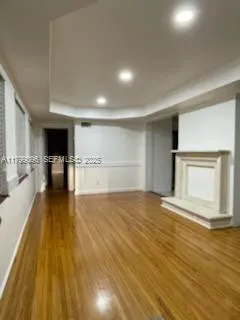 a view of empty room with wooden floor and fireplace