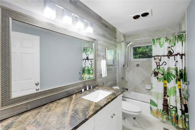 a bathroom with a granite countertop sink a toilet and shower