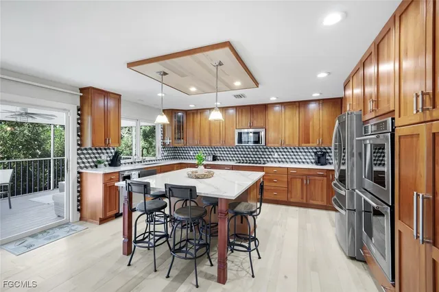 a kitchen with stainless steel appliances kitchen island granite countertop a table chairs sink and wooden cabinets