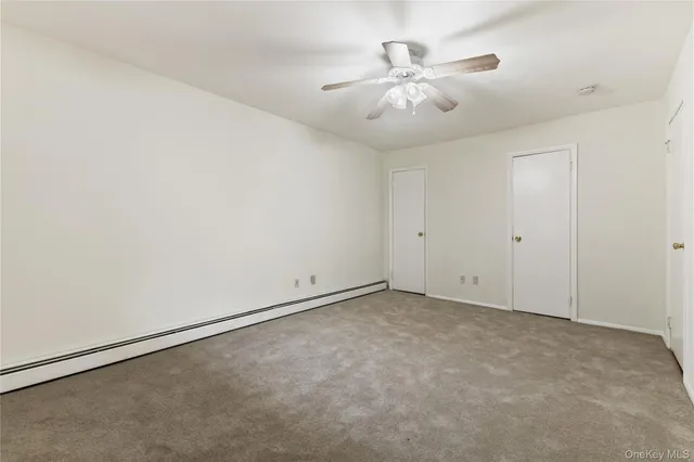an empty room with chandelier fan and window