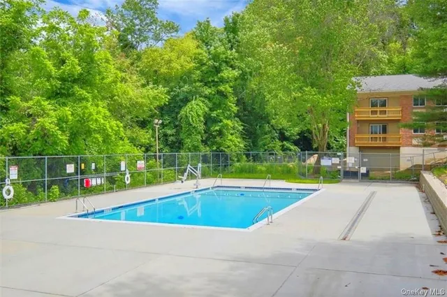 a view of pool with a bench and trees