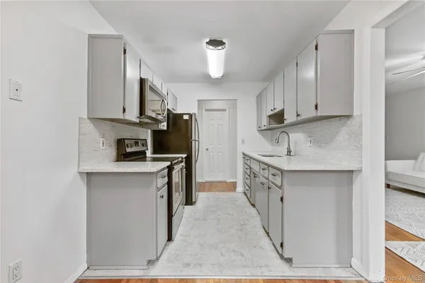 a kitchen with kitchen island granite countertop a sink a counter space stainless steel appliances and cabinets
