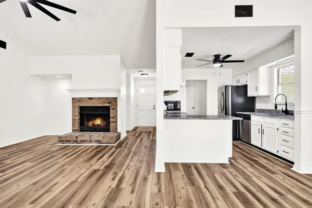 a living room with stainless steel appliances kitchen island granite countertop furniture and a fireplace