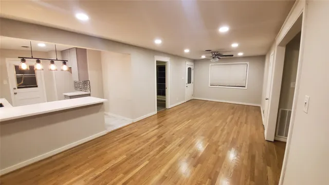 a view of a hallway to a room with wooden floor and windows
