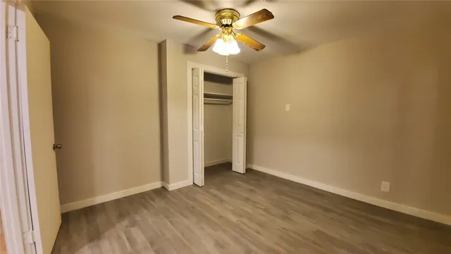 a view of a room with wooden floor and a ceiling fan