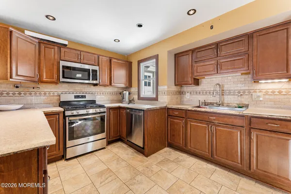 a kitchen with stainless steel appliances granite countertop a stove a sink and a microwave