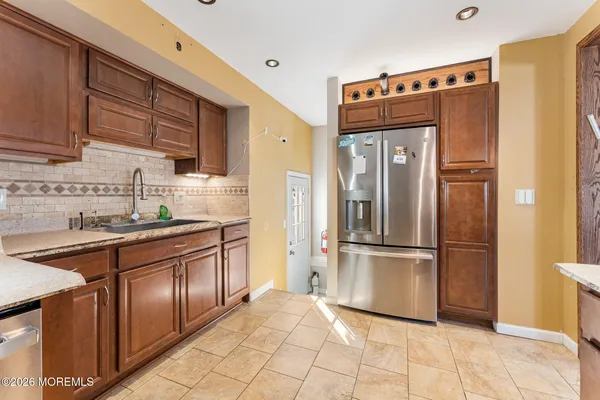 a kitchen with kitchen island granite countertop a sink cabinets and stainless steel appliances