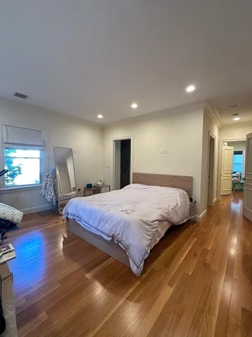 a spacious bedroom with a bed and wooden floor
