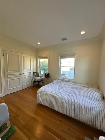 a spacious bedroom with a bed and wooden floor