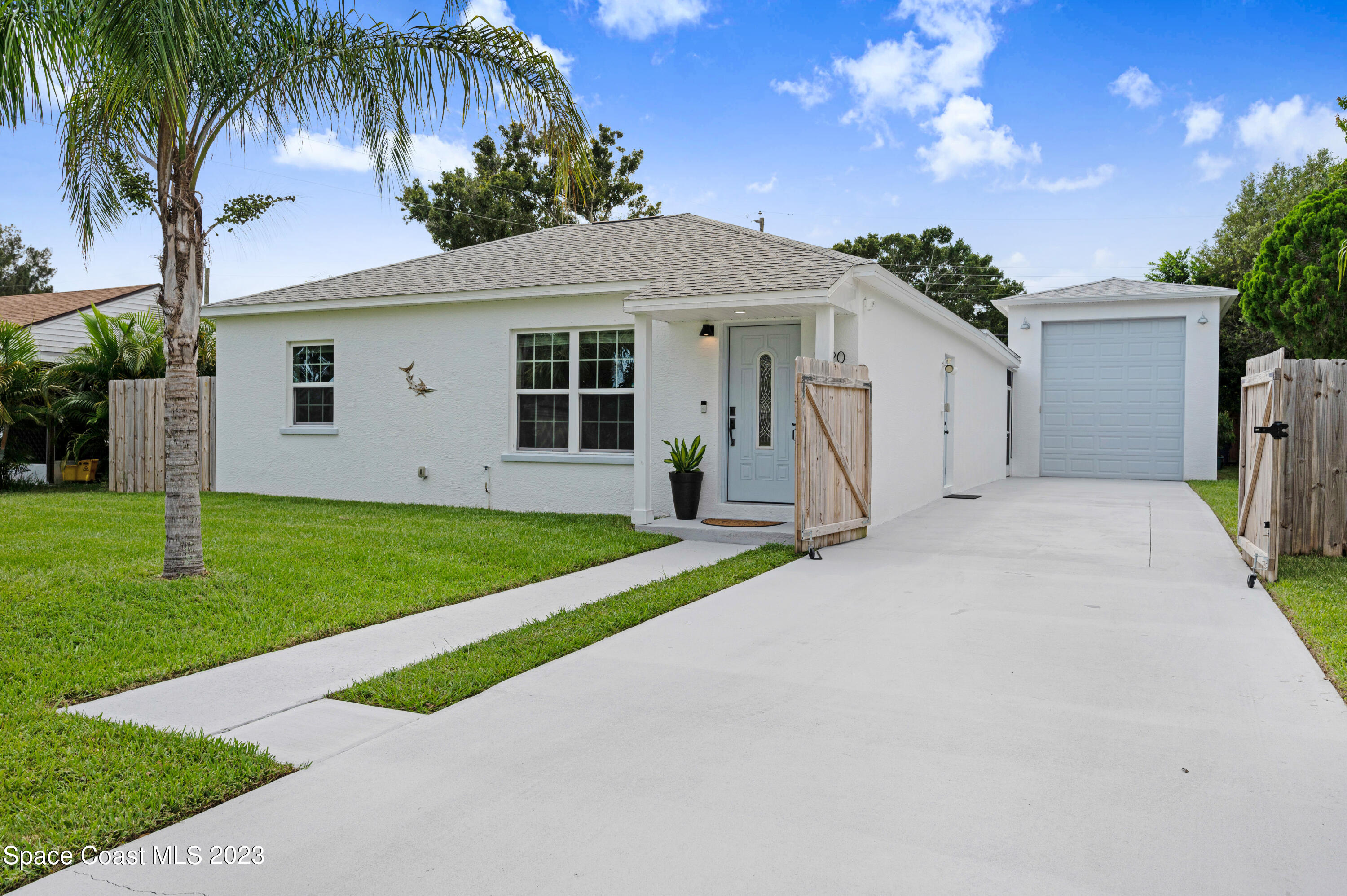 a view of a house with a yard and palm trees