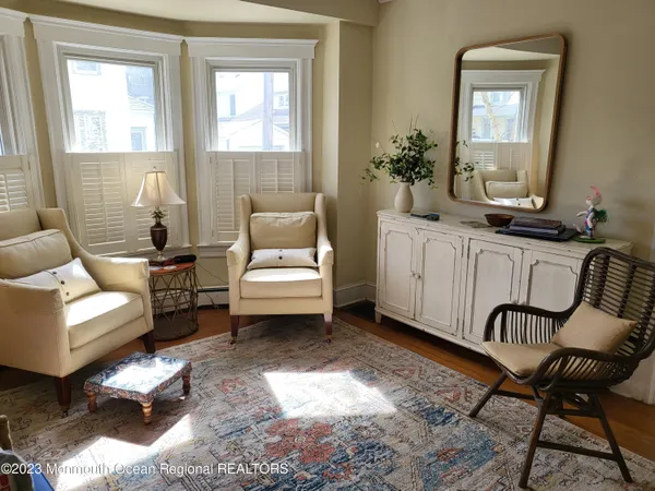 a living room with furniture and a large mirror next to a window
