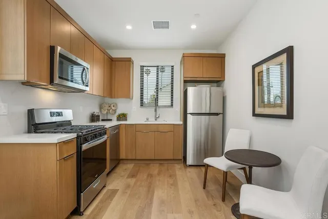 a kitchen with stainless steel appliances granite countertop a refrigerator a stove top oven a sink dishwasher and white cabinets with wooden floor