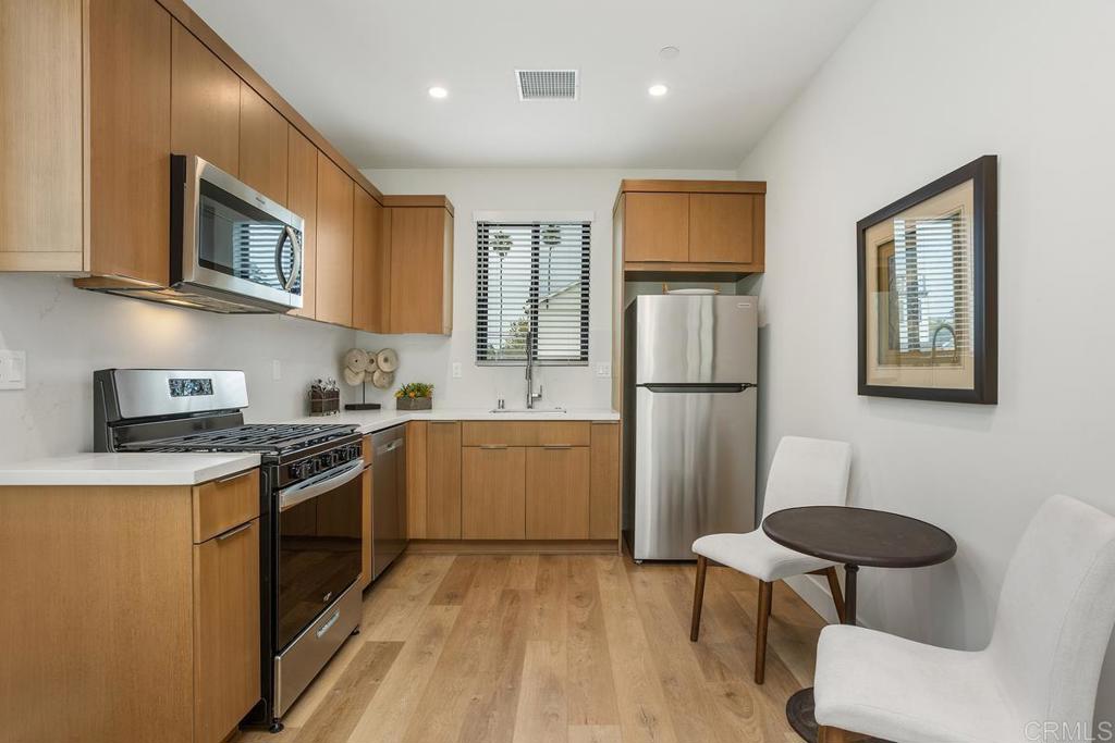 1756 Whaley Street Oceanside, CA 92054 - Photo 10 of 26 a kitchen with stainless steel appliances granite countertop a refrigerator a stove top oven a sink dishwasher and white cabinets with wooden floor