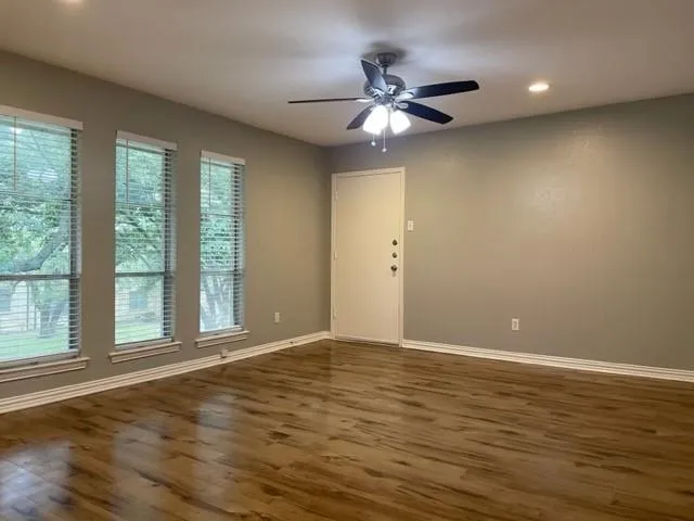 a view of an empty room with window and wooden floor