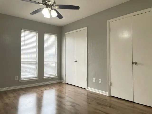 a view of an empty room with wooden floor and window