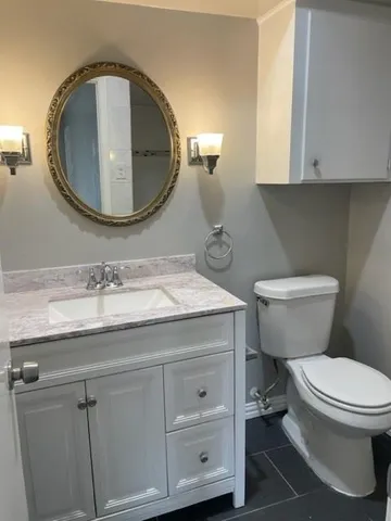 a bathroom with a granite countertop toilet sink and mirror