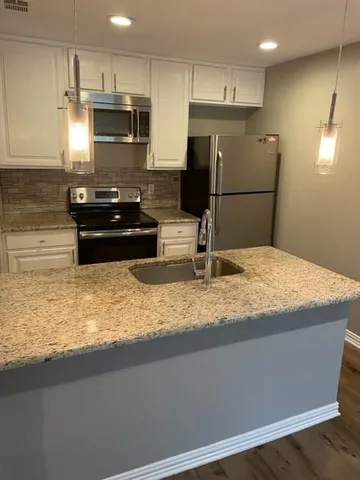 a kitchen with kitchen island granite countertop a refrigerator a stove and a sink