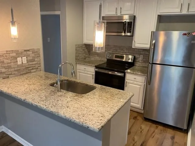 a kitchen with granite countertop a refrigerator and a sink