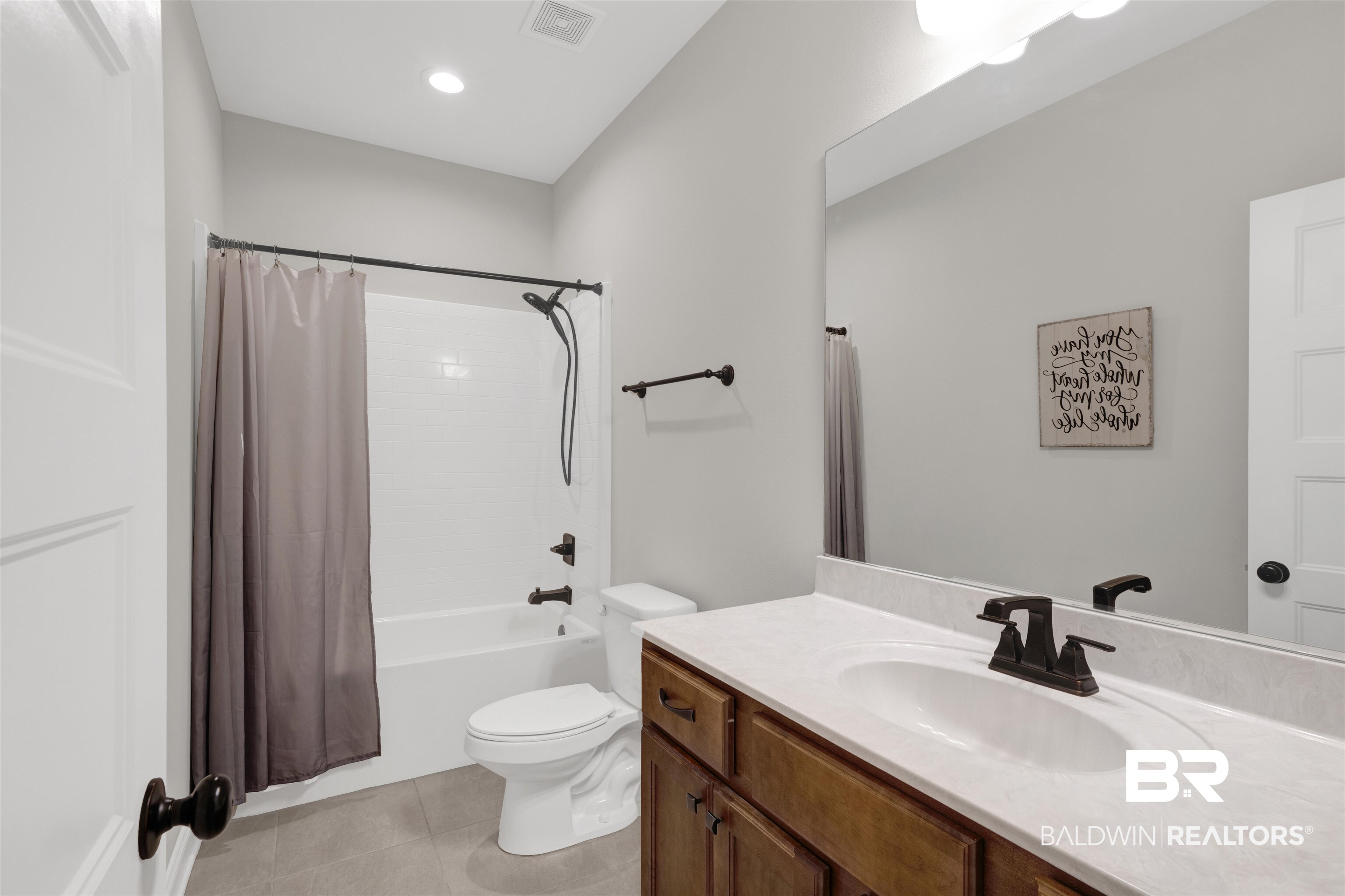 12672 Squirrel Drive Daphne, AL 36527 - Photo 28 of 49 Bathroom featuring a wood-finish vanity with a white countertop and undermount sink, a large wall-mounted mirror, and a tub/shower combination with subway tile surround